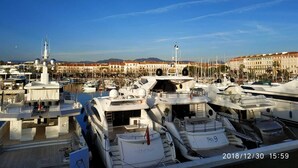 Een jachthaven met meerdere jachten die aanmeren, een heldere lucht en gebouwen op de achtergrond.