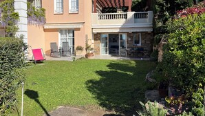 Een tweelaags huis met een balkon, een terras met tuinmeubilair en een verzorgd gazon.