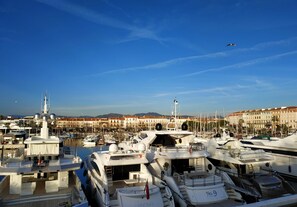 Un port de plaisance où sont amarrés de nombreux yachts, un ciel dégagé et des bâtiments en arrière-plan.