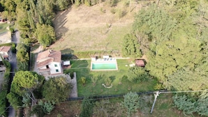 Vista aerea di un quartiere residenziale con una casa, una piscina e vegetazione circostante.