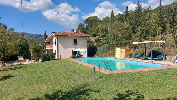 Una casa con piscina, zona relax coperta e vista sulle colline circostanti.