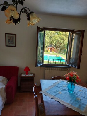 A room with a view of a swimming pool, a red sofa, a table with a blue vase, and a framed picture on the wall. - Detached property with 4 bedrooms, garden, and private pool near Lucca. (Lucca)