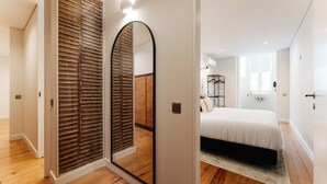 Une chambre à coucher avec un lit, un miroir, une armoire et, au fond, une salle de bain.