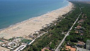 Vue aérienne d’une zone côtière avec une plage, des immeubles résidentiels et une route.