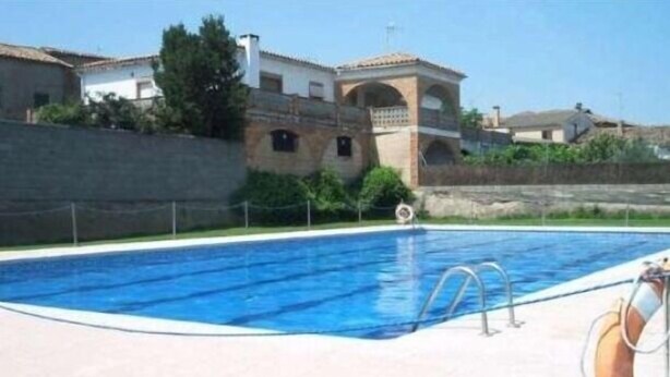 A swimming pool with a lifebuoy, surrounded by a concrete deck and a low stone wall. - Alcanadre apartment 4 people, ideal families. Pets Allowed (Angüés)