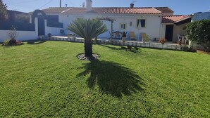 A house with a tiled roof, a well-maintained lawn, and a satellite dish.