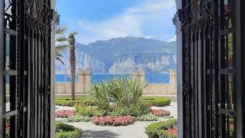 Ein kunstvoller Bogen führt in einen Garten mit Blick auf Berge und Meer.