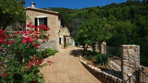 A stone building with a paved pathway leading to it, surrounded by greenery and trees. - Beatiful and peaceful villa with amazing views into the mountains  (Sóller)