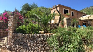 A rustic stone wall, a stone pillar, and a stone building with a tiled roof. - Beatiful and peaceful villa with amazing views into the mountains  (Sóller)
