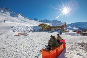 Un centro de esquí con un albergue de madera, pistas cubiertas de nieve y un cielo azul despejado.