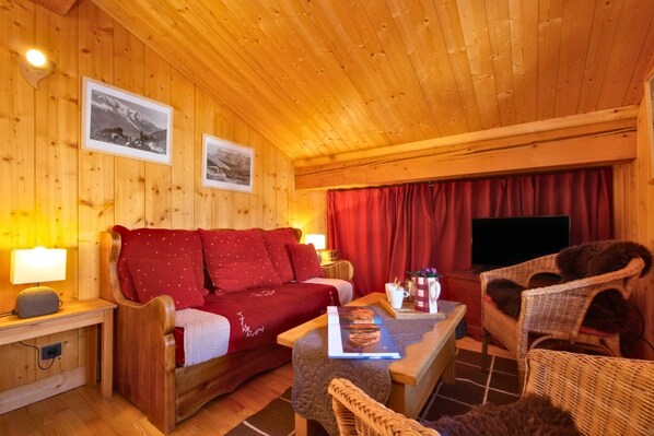 En mysig trästuga med en soffa, stolar, ett bord och en tv.