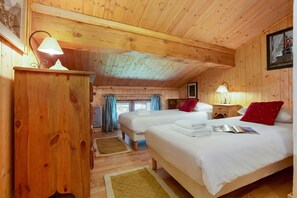 Une chambre de style cabane en bois, avec deux lits, une table de chevet et une lampe.