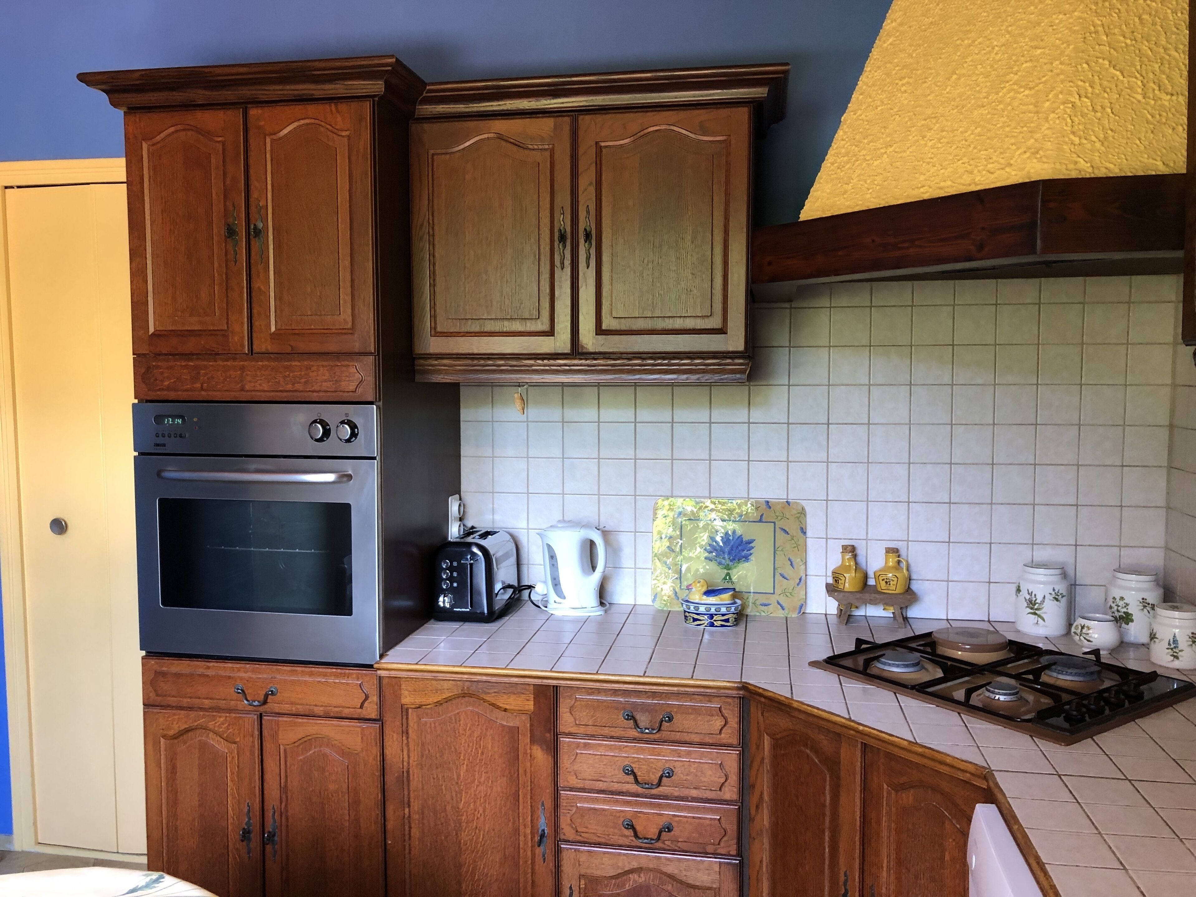 A kitchen with wooden cabinets, a stainless steel oven, a toaster, and a gas stove.