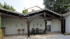 A covered patio area with a pool, featuring a wooden pergola, a table with chairs, and a small garden area. - Spacious Villa with large private Pool and Air-conditioning in all 5 bedrooms (Les Aires)