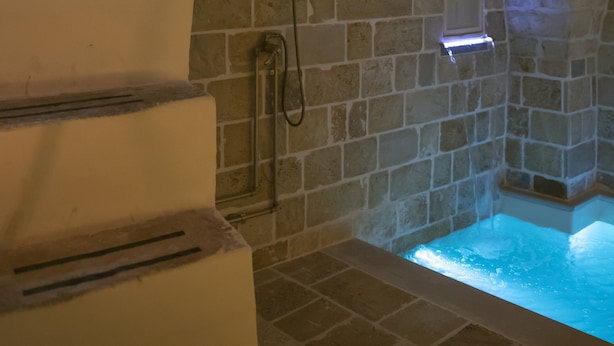 Ein Badezimmer mit Steinwänden, einer eingebauten Badewanne und einer Duschkabine.