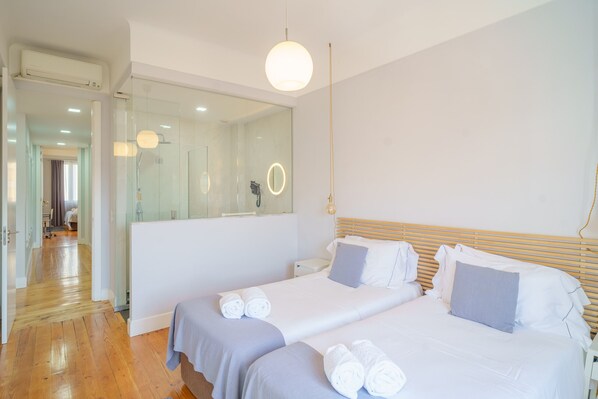 A modern hotel room with two beds, a large mirror, and a wooden floor.