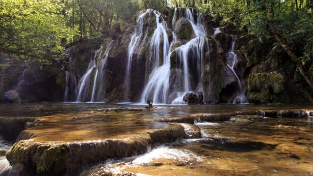 A waterfall cascading over rocks in a forested area.