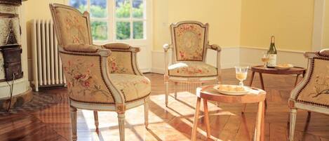 A room with two upholstered chairs, a small round table, and a radiator.