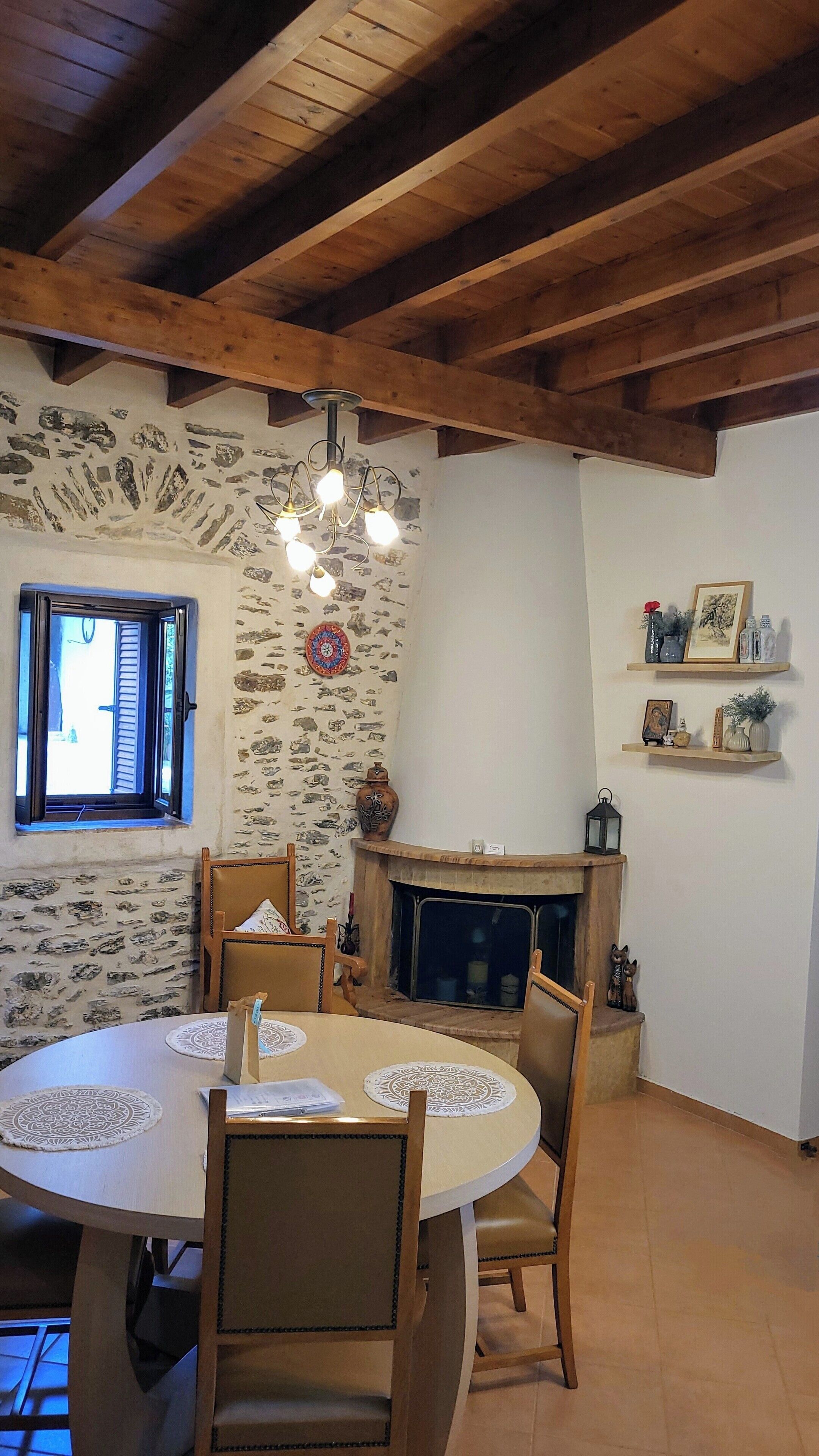 A cozy dining area with a round table, chairs, a fireplace, and stone wall decor.