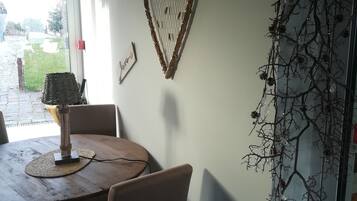 Un comedor con una mesa redonda de madera, sillas, una lámpara y una decoración en forma de corazón en la pared.