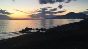 Une plage avec une montagne en arrière-plan, au coucher du soleil.