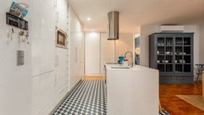 Uma cozinha moderna com armários brancos, uma ilha central, micro-ondas e forno embutido.