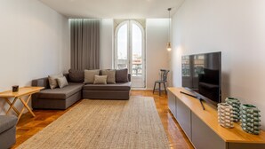 Uma sala de estar moderna com um sofá seccional, uma TV e uma mesa de centro de madeira.