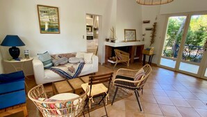 Ein geräumiges Wohnzimmer mit Sofa, Sesseln, einem Essbereich und Blick durch große Fenster.