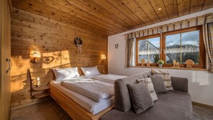 Une chambre dans une cabane en bois, avec un lit, un canapé, une fenêtre avec des rideaux et une vue sur un pont.