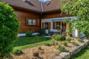 Ein Holzhaus mit Garten, einer Terrasse mit Gartenmöbeln und einer Steinmauer.