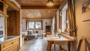 Un intérieur chaleureux avec un plancher en bois, un coin repas, un canapé et une cuisine.