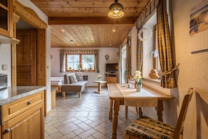 A cozy interior with wooden floors, a dining area, a sofa, and a kitchen.