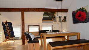 Una habitación amplia con una mesa de madera, bancos y un cuadro en la pared.