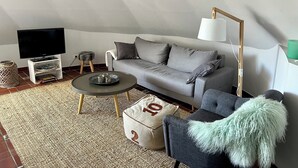 A modern living room with a grey sofa, a coffee table, and a television on a stand.