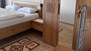 Un dormitorio con cama, armario de madera, escritorio y silla.