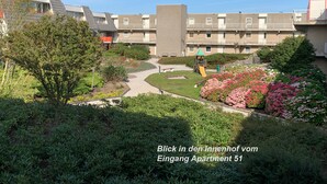 Un edificio residencial con jardín, área de juegos y un sendero que lleva a la entrada.