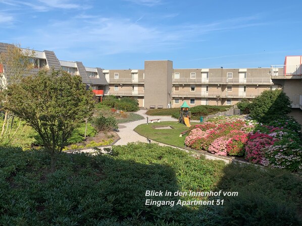 Een woongebouw met een tuin, een speeltuin en een pad naar de ingang.