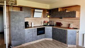 Una cocina moderna con armarios grises, encimeras de madera, horno empotrado y cafetera.