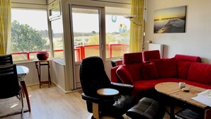 Una sala moderna con un sofá rojo, una silla negra y una mesa de madera.