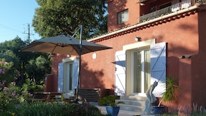 A red building with white shutters, a bench, and a statue in the garden. - Sun holidays in the calm of the French Riviera. 3 *** apartment (Les Adrets-De-L'estérel)