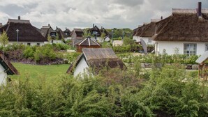 A village with traditional thatched-roof cottages, surrounded by lush greenery.