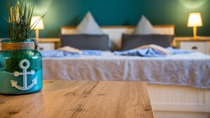A neatly made bed with pillows, a bedside lamp, and a wooden table with a decorative jar in the foreground.