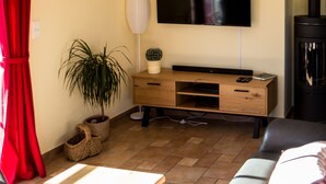 A living room with a sofa, a TV mounted on the wall, a wooden cabinet, and a red curtain.