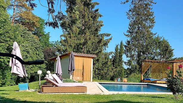 A private garden with a swimming pool, lounge chairs, and a pergola with umbrellas. - Apartment Le Solutré (Chardonnay)