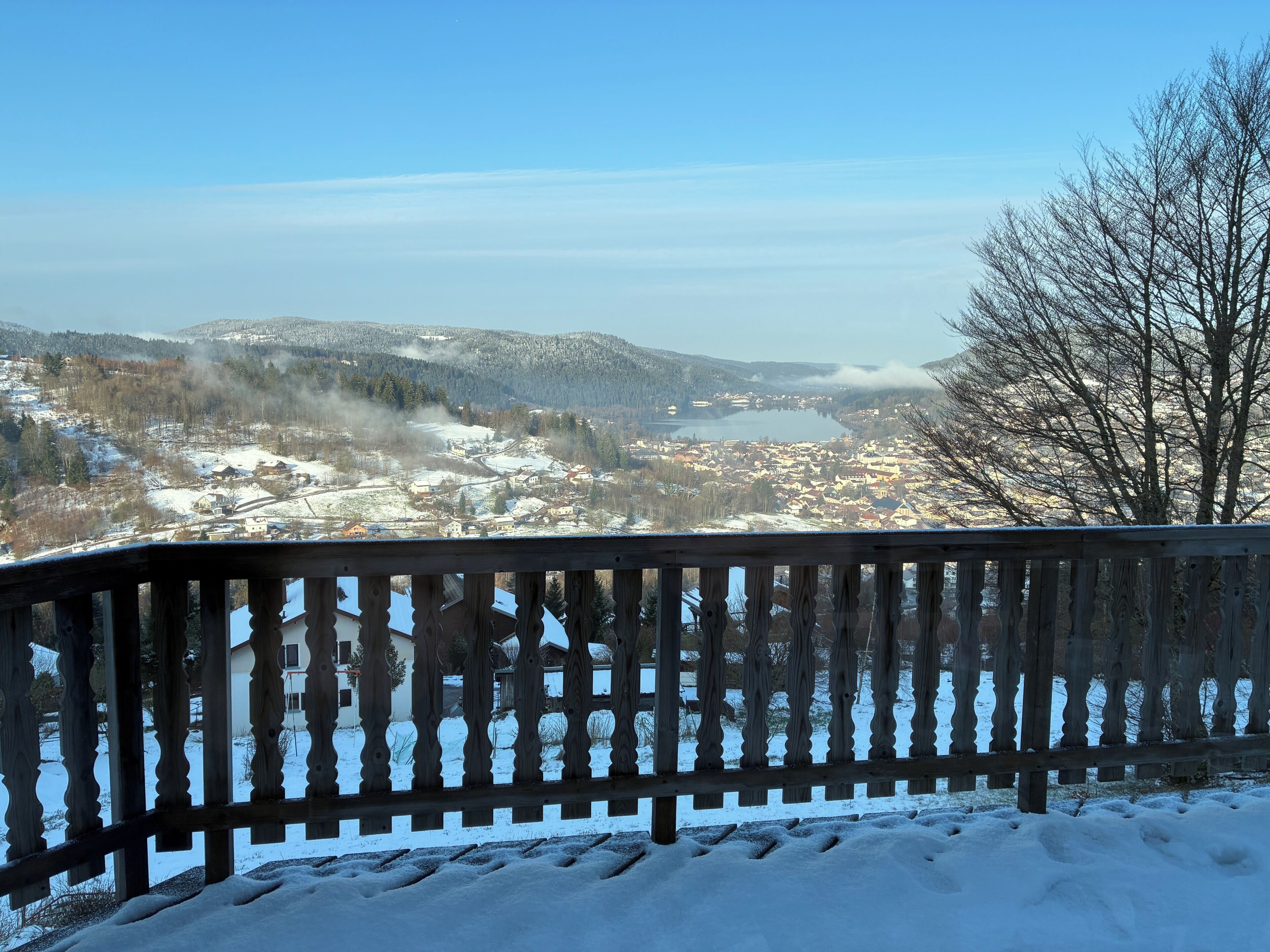 A snow-covered landscape with a wooden fence in the foreground.
