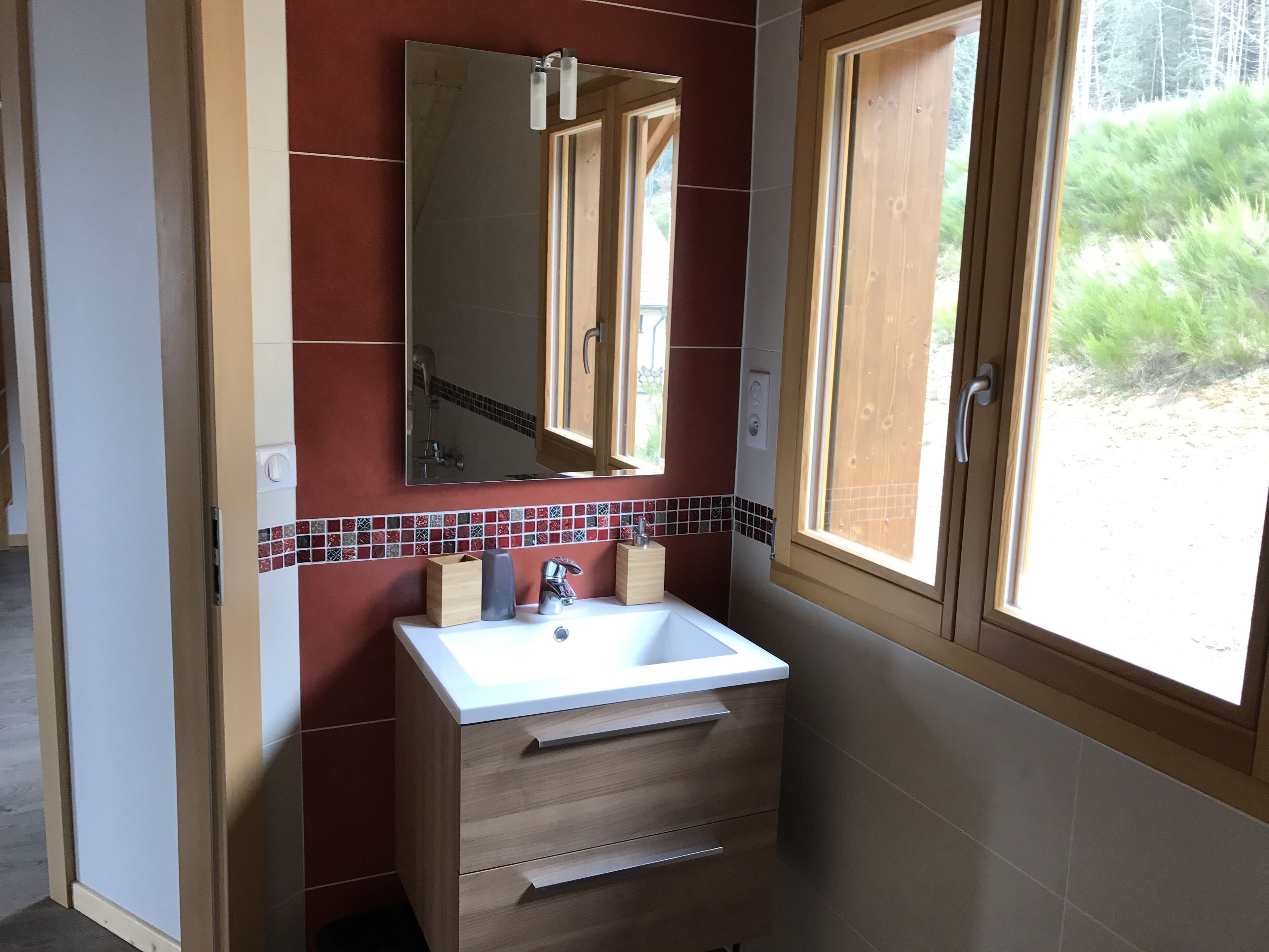 Een badkamer met een witte wastafel, een houten kastje en een grote spiegel.