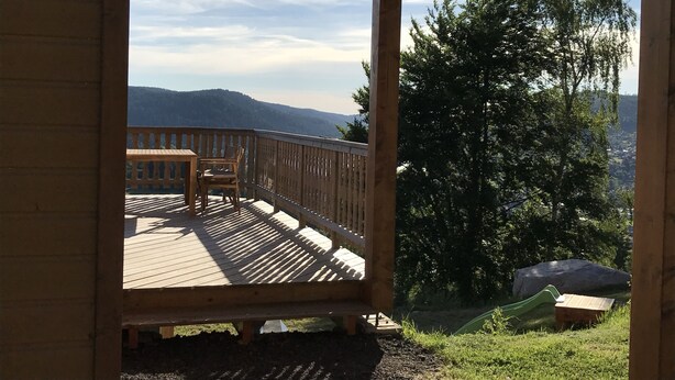 Une terrasse en bois offrant une vue sur les montagnes et les arbres.