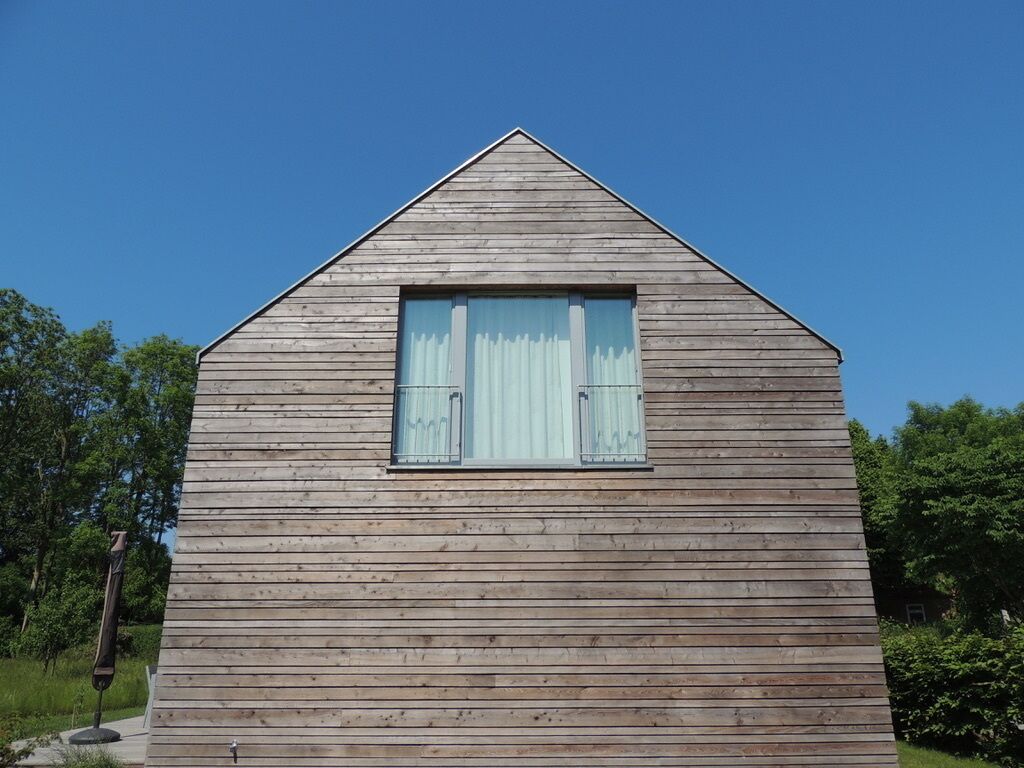 A wooden cabin with a pitched roof and a window with shutters.