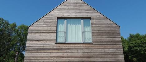 A wooden cabin with a pitched roof and a window with shutters.
