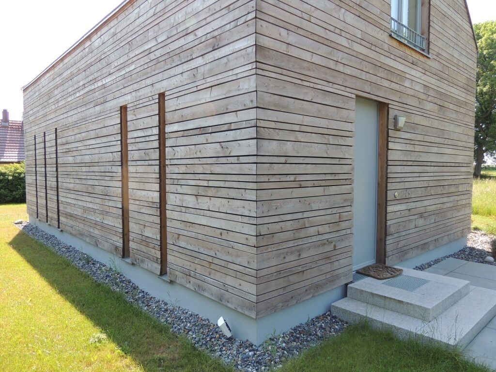 Un bâtiment moderne avec des panneaux de bois horizontaux et un petit hall d'entrée.